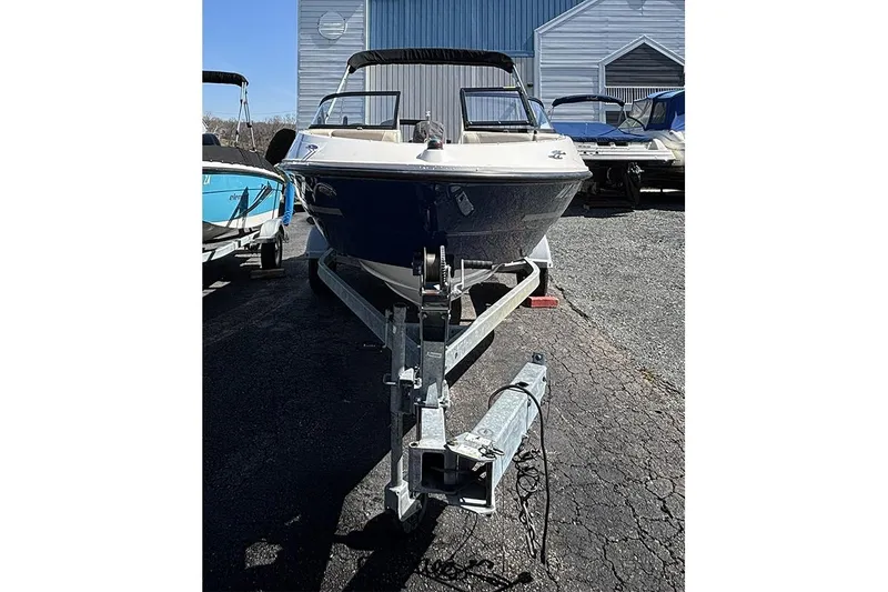 Slide: The Image of 2016 Bayliner 185 Bowrider on trailer, parked outdoors near other boats. - 2