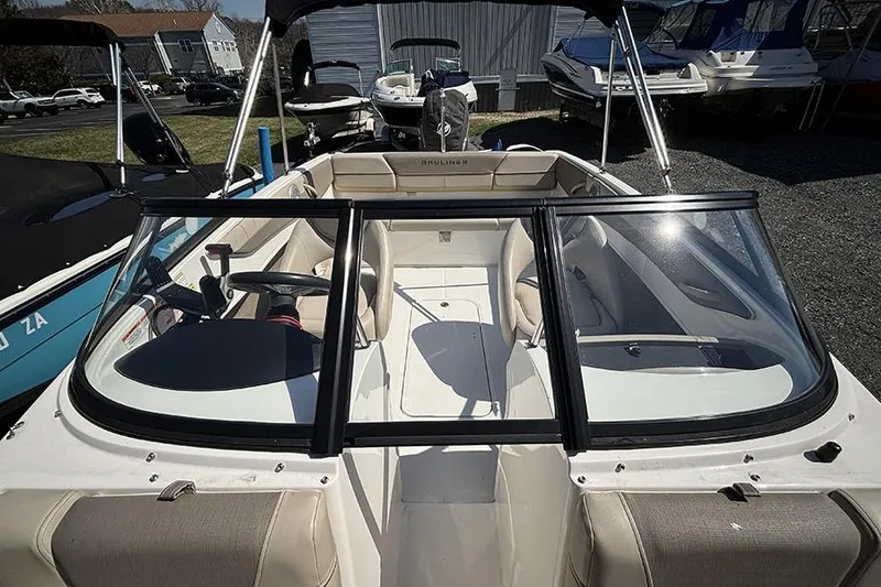 Slide: The Image of 2016 Bayliner 185 Bowrider interior with seating and steering wheel, parked outdoors. - 20