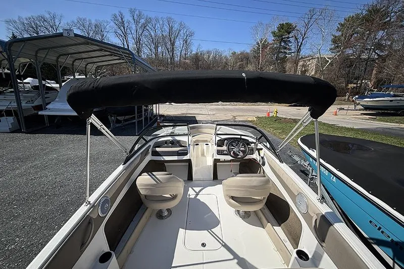 Slide: The Image of 2016 Bayliner 185 Bowrider interior with seating and steering wheel, parked outdoors. - 6