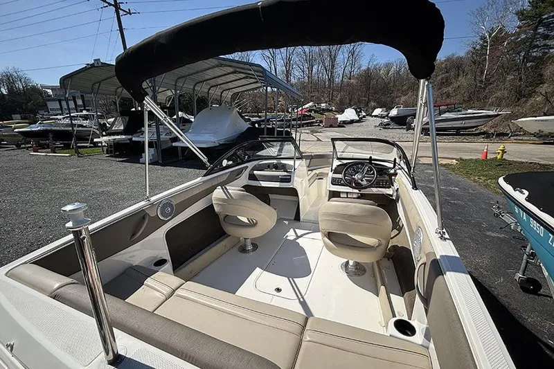 Slide: The Image of 2016 Bayliner 185 Bowrider interior with seating and steering wheel, parked outdoors. - 7