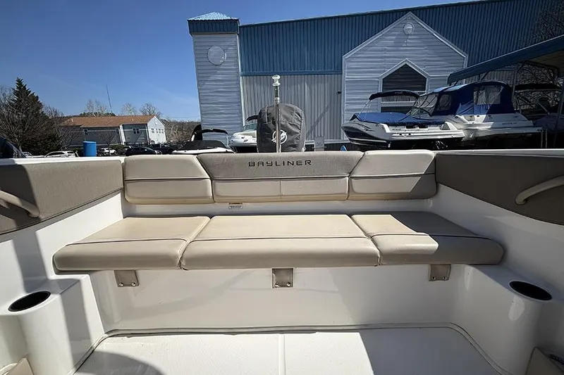Slide: The Image of 2016 Bayliner 185 Bowrider interior with beige seating, docked near blue building. - 8