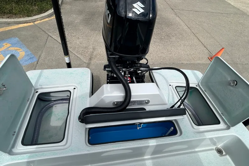 Slide: The Image of 2026 Gulf Coast Saber Cat boat with Suzuki outboard motor and open storage compartments. - 10