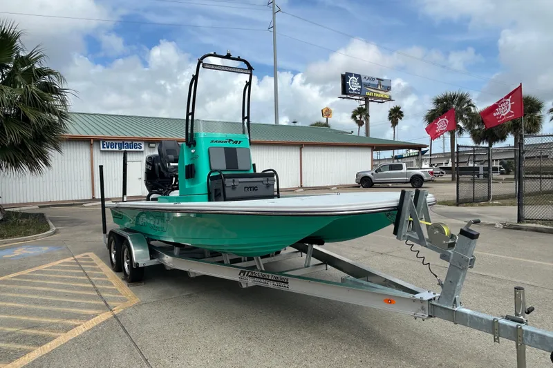Slide: The Image of 2026 Gulf Coast Saber Cat boat on trailer in parking lot, under cloudy sky. - 4