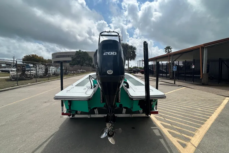 Slide: The Image of 2026 Gulf Coast Saber Cat boat with powerful 200 HP engine, parked outdoors. - 7