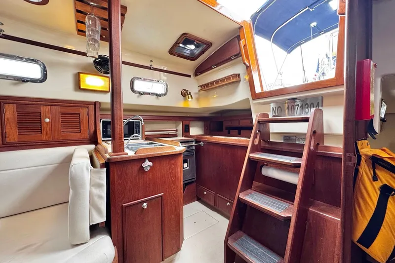 Slide: The Image of Interior of 1998 Island Packet 350 sailboat with wood paneling and white seating. - 16
