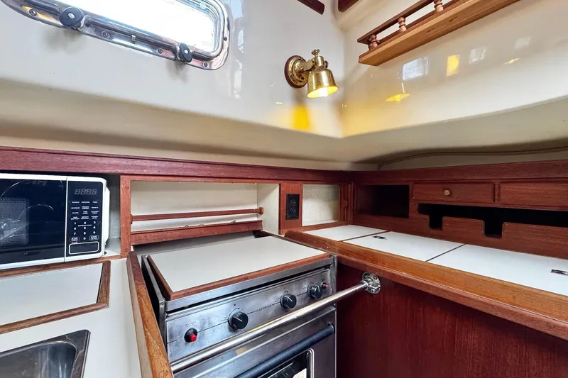 Slide: The Image of Interior of 1998 Island Packet 350 sailboat galley with wood cabinetry and stove. - 19