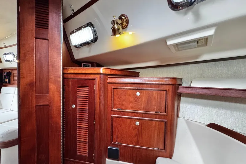 Slide: The Image of Interior of 1998 Island Packet 350 sailboat with wood paneling and white seating. - 35
