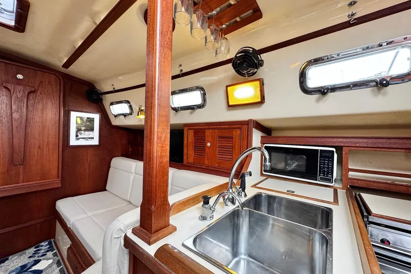 Slide: The Image of Interior of 1998 Island Packet 350 sailboat with wood finish and white seating. - 8
