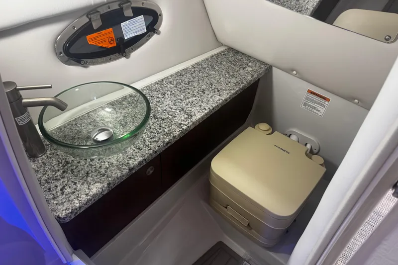 Slide: The Image of 2024 Crownline 250 XSS boat bathroom with granite countertop and glass sink. - 2