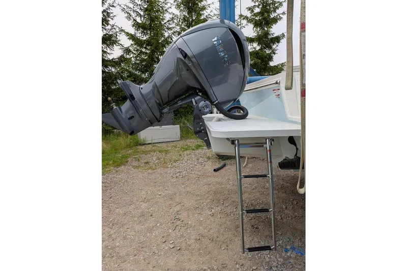 Slide: The Image of Outboard motor on 2026 Parker 227 Explorer boat with ladder, parked on gravel. - 6