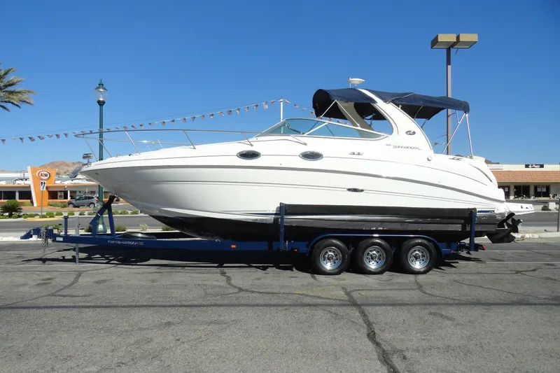 The Image of 2004 Sea Ray Sundancer 280 boat on trailer, parked in urban setting under clear blue sky. - 1