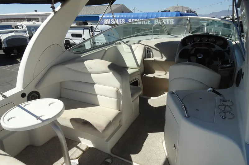Slide: The Image of 2004 Sea Ray Sundancer 280 interior with seating, helm, and table in a marina setting. - 16