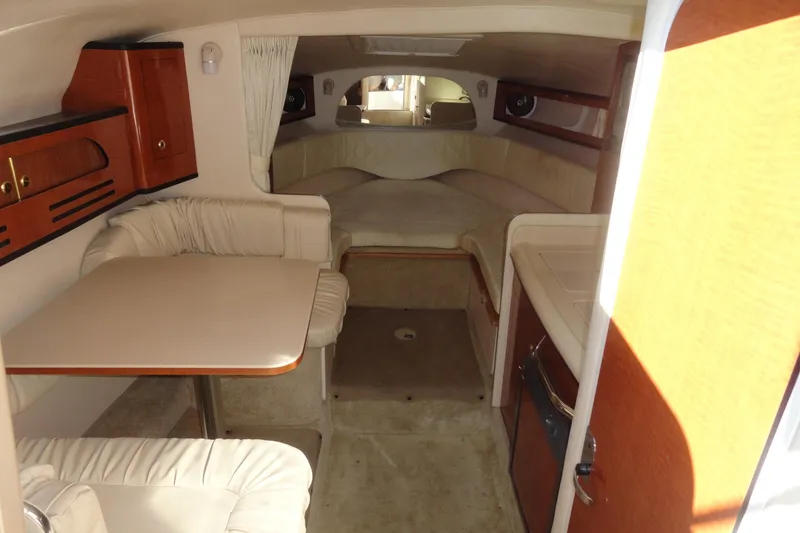 Slide: The Image of Interior of 2004 Sea Ray Sundancer 280, featuring cozy seating and wooden cabinetry. - 18
