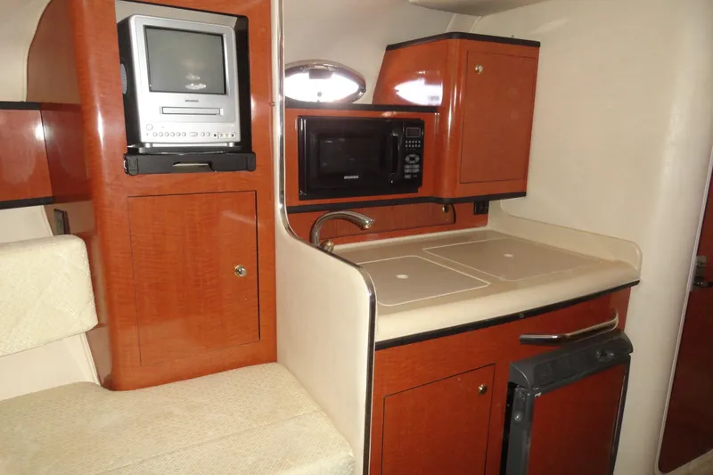 Slide: The Image of 2004 Sea Ray Sundancer 280 interior with kitchenette, featuring microwave and TV. - 19