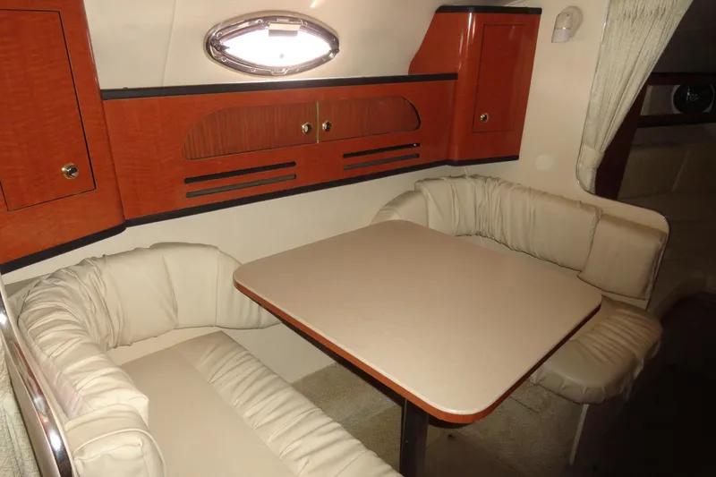 Slide: The Image of 2004 Sea Ray Sundancer 280 interior with cozy dining area and elegant wood cabinetry. - 21