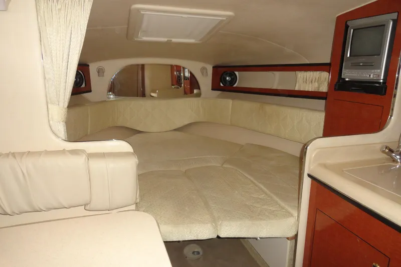 Slide: The Image of 2004 Sea Ray Sundancer 280 cabin interior with bed, TV, and kitchenette. - 23