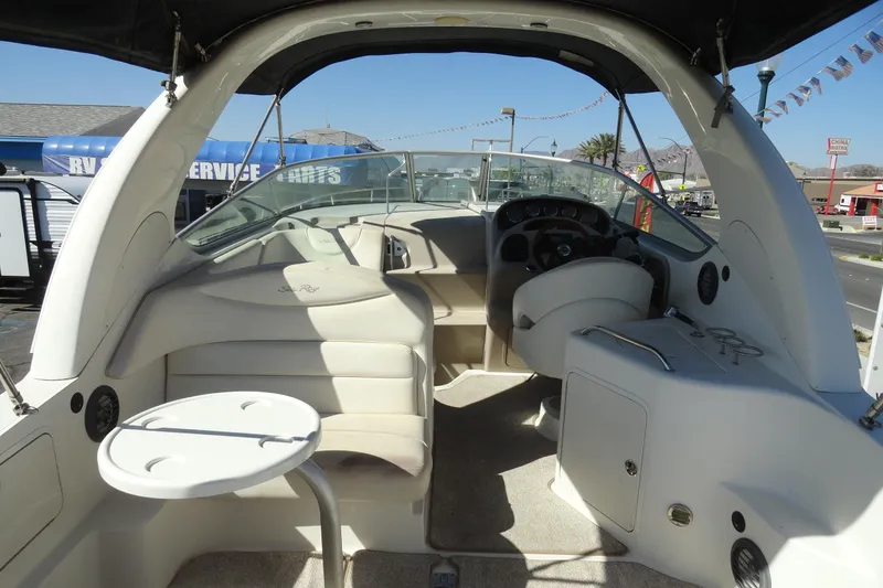 Slide: The Image of 2004 Sea Ray Sundancer 280 boat interior with seating and helm, parked outdoors. - 6