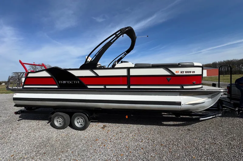 Slide: The Image of 2024 Trifecta 25ULE SS pontoon boat on trailer under clear blue sky. - 12