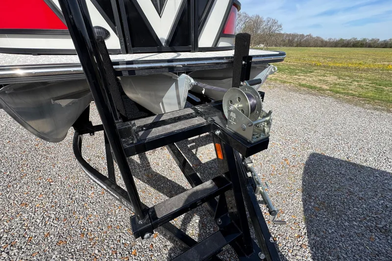 Slide: The Image of 2024 Trifecta 25ULE SS boat trailer hitch and winch on gravel driveway. - 22