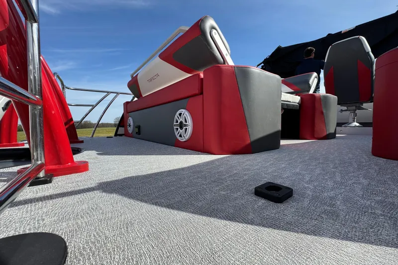 Slide: The Image of 2024 Trifecta 25ULE SS pontoon boat interior with red and gray seating under clear blue sky. - 24