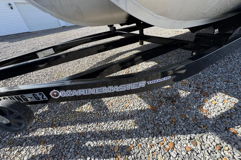 Slide: The Image of Trailer for 2024 Trifecta 25ULE SS pontoon boat on gravel surface. - 25