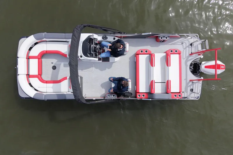 Slide: The Image of 2024 Trifecta 25ULE SS pontoon boat, aerial view, on water, featuring red and white seating. - 4
