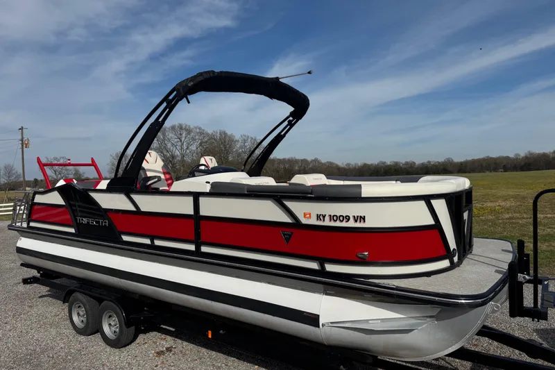 Slide: The Image of 2024 Trifecta 25ULE SS pontoon boat on trailer, featuring sleek red and white design. - 5