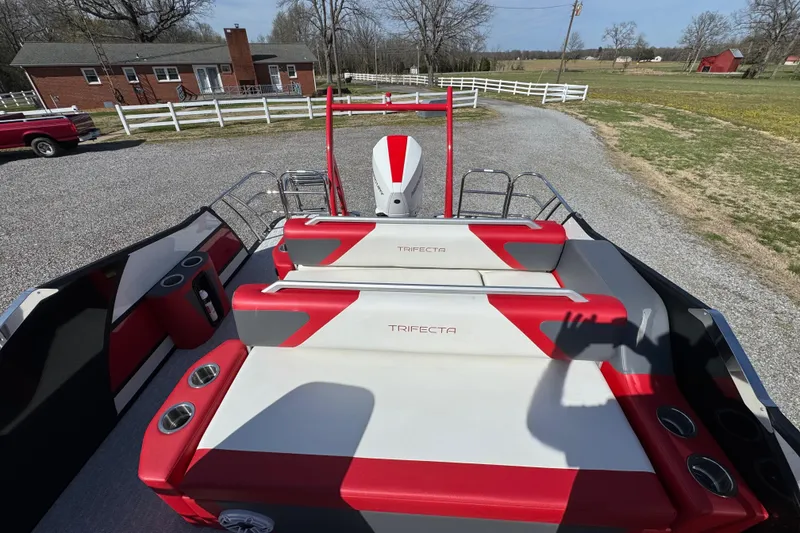 Slide: The Image of 2024 Trifecta 25ULE SS boat with red and white seating, parked outdoors. - 58