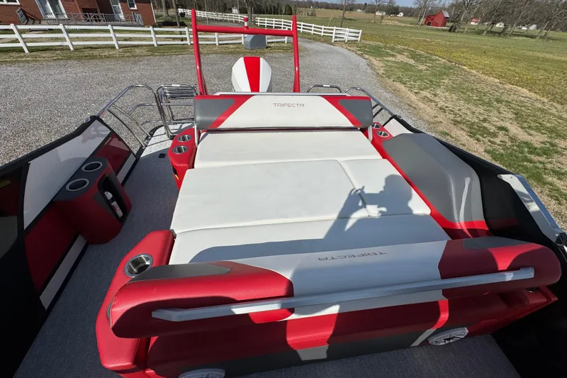 Slide: The Image of 2024 Trifecta 25ULE SS boat with red and white seating, parked outdoors. - 60