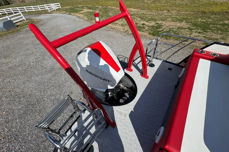 Slide: The Image of 2024 Trifecta 25ULE SS boat with Mercury engine, red accents, and ladder on gravel surface. - 68