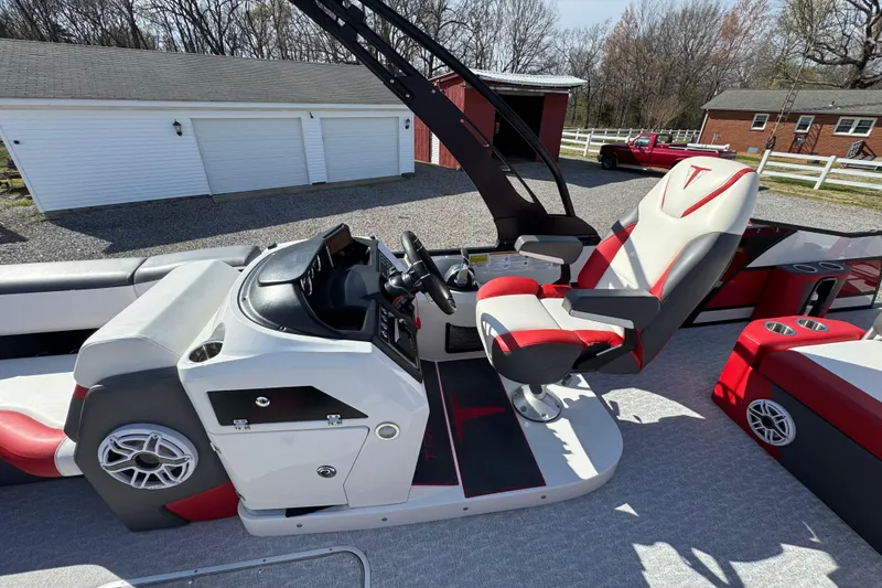 Slide: The Image of 2024 Trifecta 25ULE SS boat interior with modern helm and seating, parked outdoors. - 74