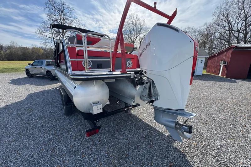 Slide: The Image of 2024 Trifecta 25ULE SS pontoon boat with Mercury outboard motor on gravel driveway. - 8
