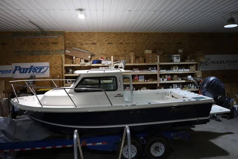 Slide: The Image of 2026 Parker 227 Explorer boat in a workshop, surrounded by shelves and equipment. - 2