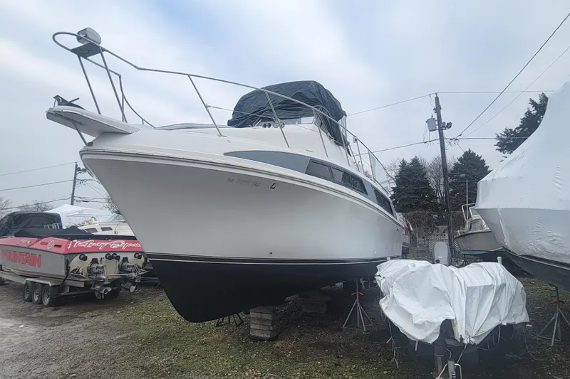 Slide: The Image of 1996 Carver 330 Mariner yacht on land, surrounded by other boats, under a cloudy sky. - 58