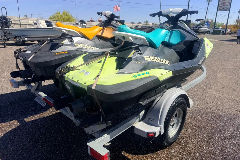 Slide: The Image of 2018 Sea-Doo Spark 2up jet skis on a trailer, parked outdoors. - 2