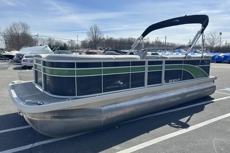 Slide: The Image of 2020 Bennington 21 SL pontoon boat parked in a lot under a clear sky. - 6