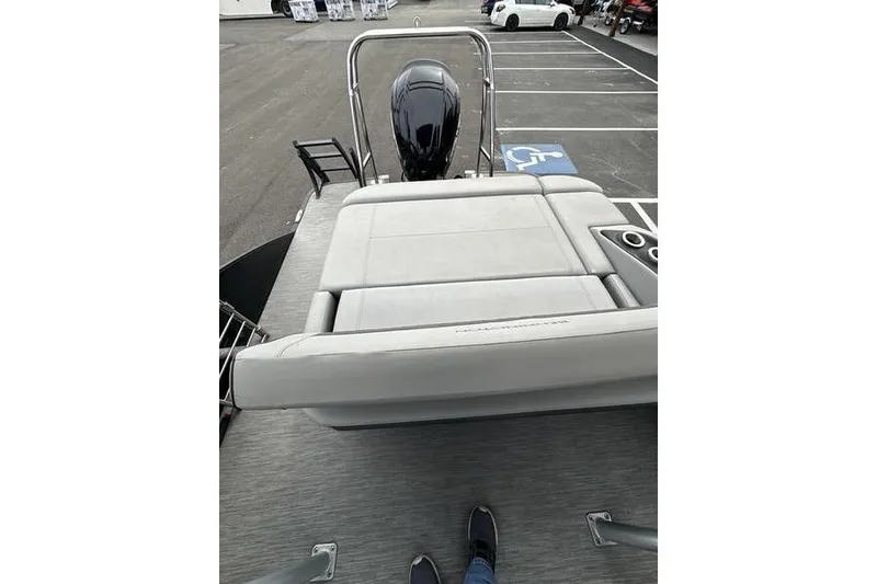 Slide: The Image of 2022 Bennington 24 LSBA boat with rear seating and outboard motor in parking lot. - 24