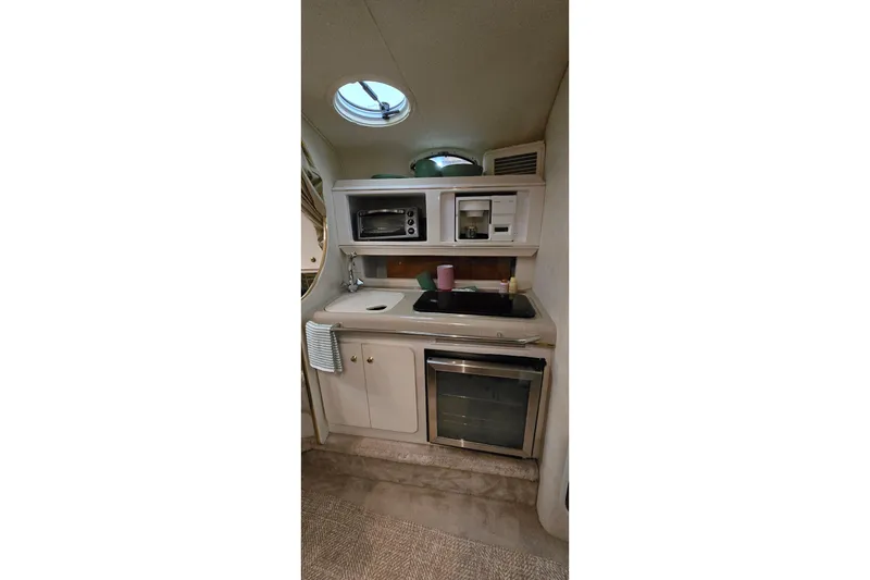 Slide: The Image of Compact kitchen area in a 2000 Monetery 302 Express boat, featuring sink, microwave, and oven. - 27