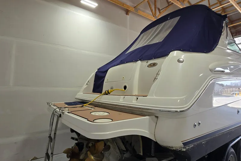 Slide: The Image of 2000 Monterey 302 Express boat in storage, featuring a blue canvas cover. - 4