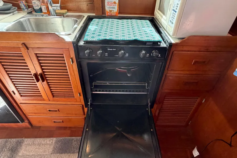 Slide: The Image of Kitchen area of 1985 Albin 36 Trawler with stove, sink, and wooden cabinetry. - 24