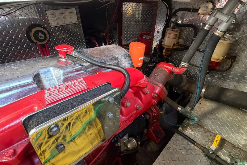 Slide: The Image of Engine compartment of a 1985 Albin 36 Trawler with red engine components and metal paneling. - 47