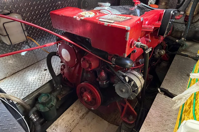 Slide: The Image of Engine room of a 1985 Albin 36 Trawler with a red engine and metal flooring. - 49