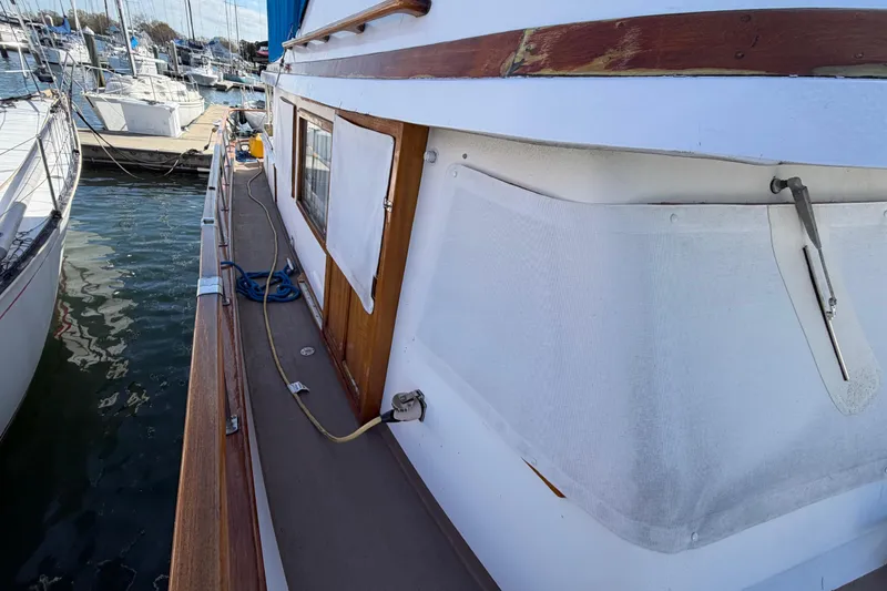 Slide: The Image of 1985 Albin 36 Trawler docked, showcasing side deck and wooden details. - 7