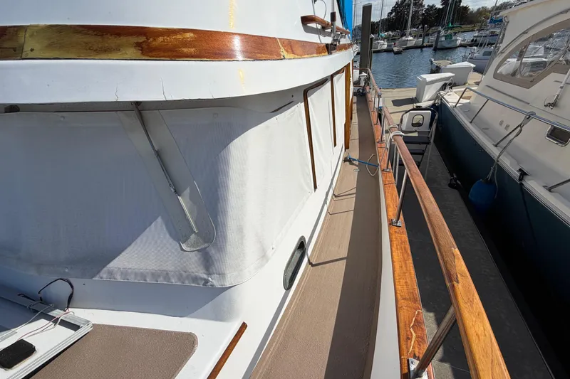 Slide: The Image of 1985 Albin 36 Trawler docked at marina, showcasing wooden railings and side deck. - 8