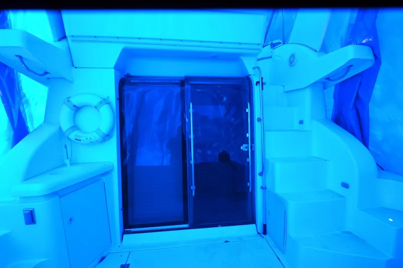 Slide: The Image of 1999 Cruisers Yachts 3585 Flybridge interior with blue lighting, featuring stairs and a life preserver. - 12