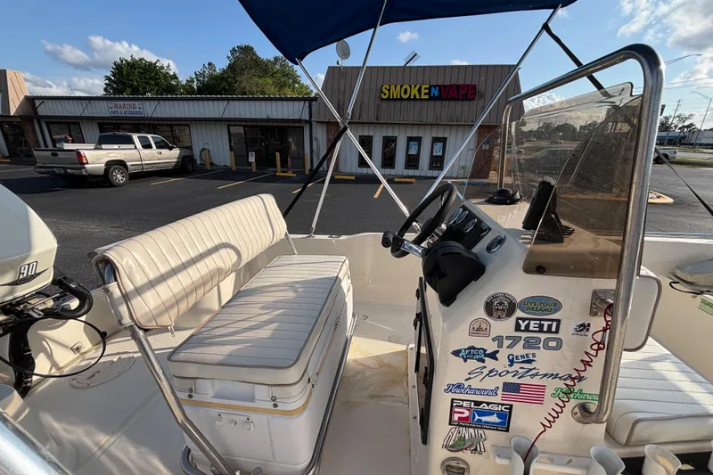 Slide: The Image of 2000 Key West 1720 Center Console boat with stickers, parked near a store. - 14