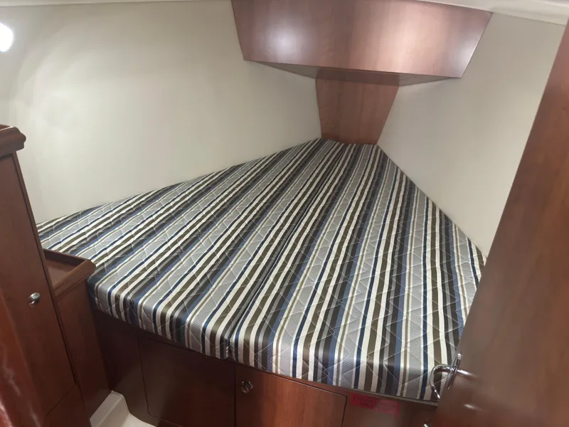 Slide: The Image of 2017 Marlow-Hunter 31 interior cabin with striped bedding and wooden cabinetry. - 11
