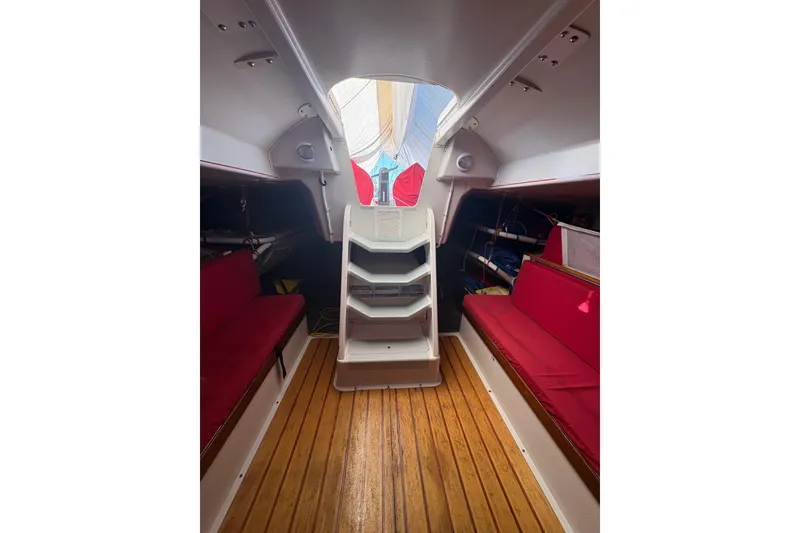 Slide: The Image of Interior of 1999 Laurie Davidson TP-52 sailboat with red seating and wooden flooring. - 2