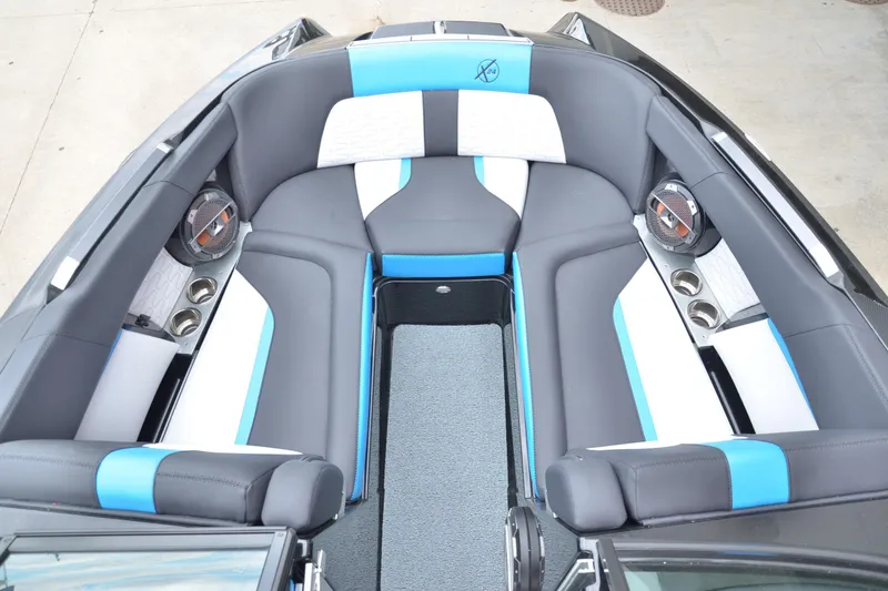 Slide: The Image of 2020 MasterCraft X24 boat interior with gray and blue seating, cup holders, and speakers. - 6