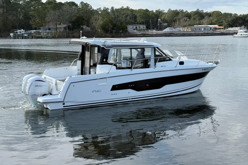 Slide: The Image of 2025 Jeanneau NC 1095 Coupe boat on calm water, featuring sleek design and twin engines. - 3